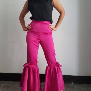 Peut inclure: Un pantalon large rose vif &agrave; taille haute et ourlet &agrave; volants. Le pantalon a un d&eacute;tail de n&oelig;ud sur chaque c&ocirc;t&eacute; de l'ourlet.