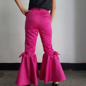 Peut inclure: Pantalon en satin rose avec une jambe large et un grand n&oelig;ud en bas de chaque jambe.