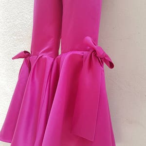 Peut inclure: Pantalon large fuchsia rose &agrave; jambes larges avec un ourlet &eacute;vas&eacute; et un d&eacute;tail de n&oelig;ud en bas de chaque jambe.