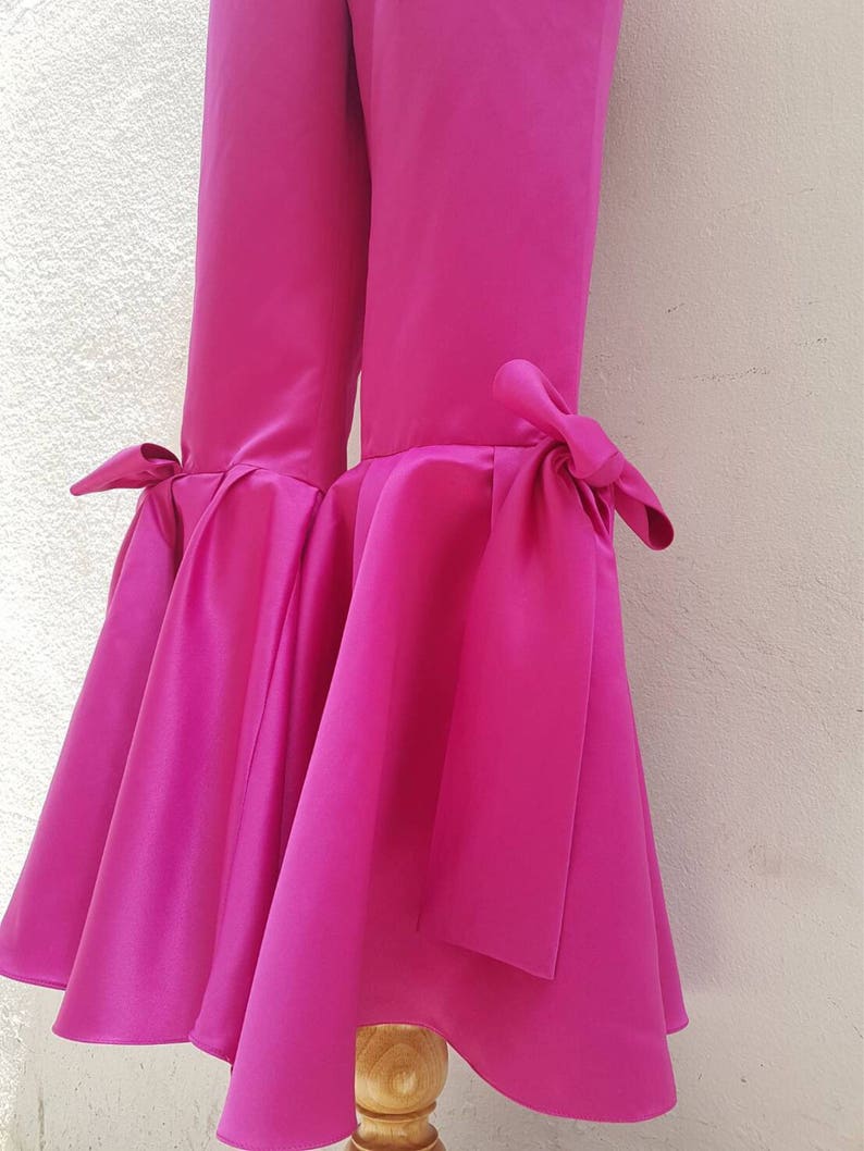 Peut inclure: Pantalon large fuchsia rose &agrave; jambes larges avec un ourlet &eacute;vas&eacute; et un d&eacute;tail de n&oelig;ud en bas de chaque jambe.