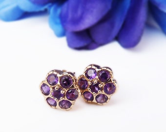 Könnte beinhalten: Ein Paar goldene Ohrringe mit einem Blumenmuster. Jeder Ohrring hat sieben violette Amethyststeine, die in eine goldene Blumenform gefasst sind.