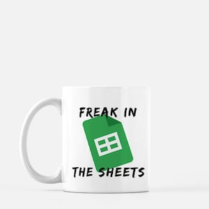 Könnte beinhalten: Weiße Keramiktasse mit einem grünen Google Sheets-Symbol und dem Text "Freak in the Sheets" in Schwarz.