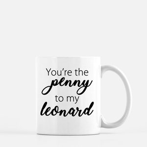 Può includere: Una tazza in ceramica bianca con una scritta nera che dice "You're the penny to my Leonard".
