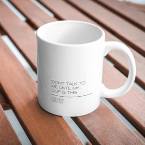 May include: White ceramic coffee mug with black text that reads "Don't talk to me until my cup is this EMPTY".