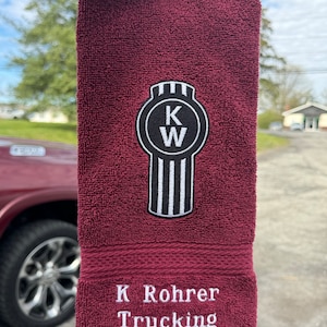May include: A maroon hand towel with a white embroidered KW logo and the text "K Rohrer Trucking".