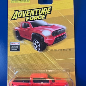 May include: An Adventure Force Toyota Tacoma TRD Pro toy truck in red, packaged on a yellow blister card. The packaging features the Adventure Force logo, a Toyota official licensed product label, and a warning about small parts for ages 3 and up.