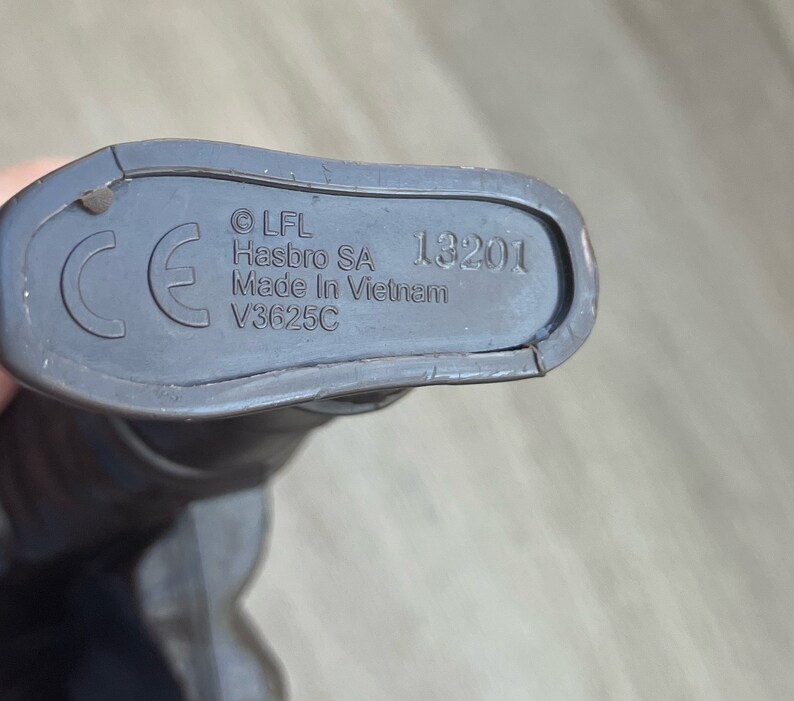 May include: Close-up of the bottom of a toy, showing the CE mark, copyright information, and the text "LFL Hasbro SA Made in Vietnam V3625C 13201".