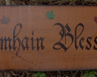 May include: A wooden sign with the text "Samhain Blessings" in black script. The sign is painted in a warm brown color and has three small painted leaves in green, red, and orange.