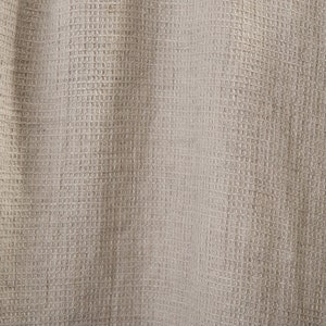 May include: A close-up of a beige woven fabric with a textured surface. The fabric has a subtle sheen and a slightly rough texture.