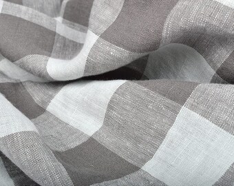 May include: A close-up of a white and gray checkered fabric. The fabric is woven with a subtle texture and has a soft, drapey feel.