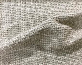 Pode incluir: Um close-up de um tecido bege de tecido waffle. O tecido tem um padrão tecido texturizado.