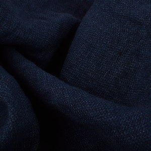 Op de afbeelding: Een close-up van een donkerblauwe stof met een textuur. De stof is zacht en heeft een licht gerimpeld uiterlijk.