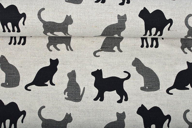 May include: A white fabric with a repeating pattern of black cat silhouettes. The cats are in various poses, including sitting, standing, and walking.
