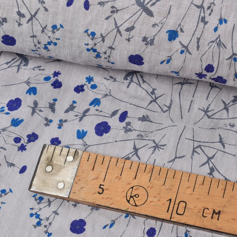 Puede incluir: Tela gris con un patr&oacute;n floral azul. Una regla de madera con el texto "10 cm" est&aacute; encima de la tela.
