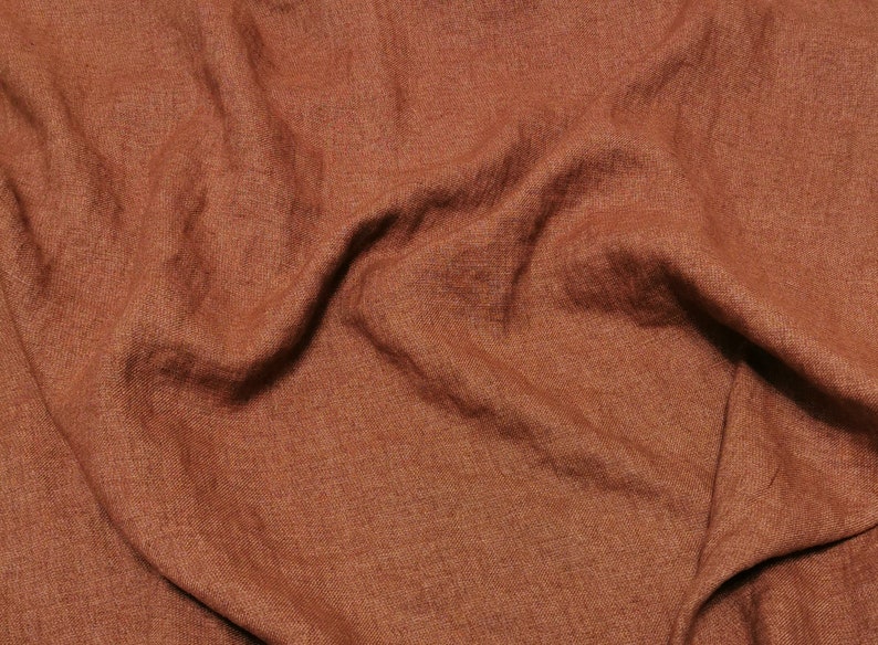 Puede incluir: Primer plano de una tela de lino marr&oacute;n con una superficie texturizada. La tela est&aacute; arrugada y tiene un aspecto natural y r&uacute;stico.