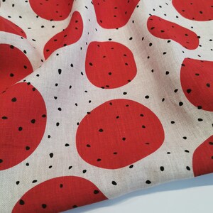 May include: Red and white fabric with a repeating pattern of red circles with black dots. The fabric is folded in half.