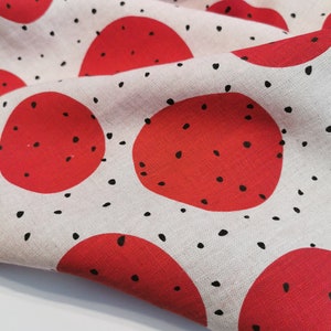 May include: White fabric with a repeating pattern of red circles with black dots. The fabric is folded and the circles are overlapping.