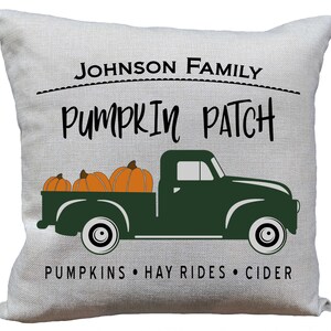 May include: A white pillow with the text "JOHNSON FAMILY PUMPKIN PATCH PUMPKINS HAY RIDES CIDER" and a green truck with three orange pumpkins in the bed.