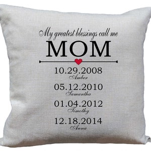 Może przedstawiać: Biała poduszka z napisem "My greatest blessings call me MOM" i czerwonym sercem. Pod tekstem znajdują się daty i imiona czworga dzieci: 10.29.2008 Amber, 05.12.2010 Samantha, 01.04.2012 Timothy i 12.18.2014 Anna.