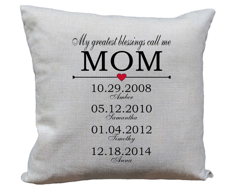 Może przedstawiać: Biała poduszka z napisem "My greatest blessings call me MOM" i czerwonym sercem. Pod tekstem znajdują się daty i imiona czworga dzieci: 10.29.2008 Amber, 05.12.2010 Samantha, 01.04.2012 Timothy i 12.18.2014 Anna.
