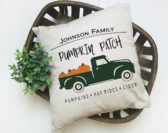 May include: A white pillow with the text "JOHNSON FAMILY PUMPKIN PATCH" and a green truck carrying pumpkins. The text below the truck reads "PUMPKINS HAY RIDES CIDER".