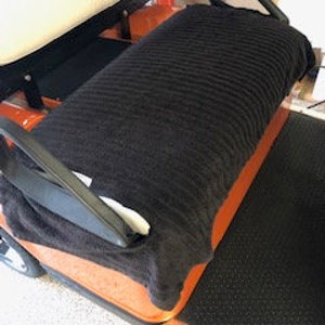 May include: Black ribbed golf cart seat cover. The cover is made of a soft, plush material and is designed to protect the seat from dirt, spills, and wear and tear.