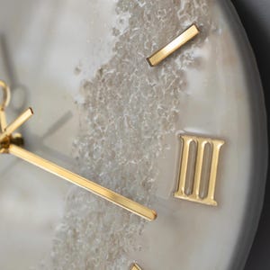 Close-up of the clock's hands and Roman numeral markers, with a focus on the luxurious finish.