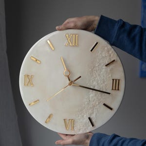 A person holding the handcrafted marble resin clock, showcasing its delicate details and size.