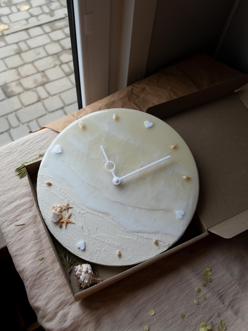 Beige resin wall clock with ocean-inspired design, featuring natural shells, starfish, and waves