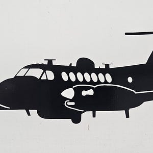 May include: Black silhouette of a small twin-engine turboprop aircraft with a high wing design. The aircraft has a single propeller on each engine.