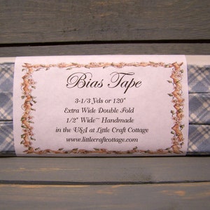 May include: A package of blue and white plaid bias tape, 3-1/3 yards or 120 inches long. It is extra wide double fold, 1/2 inch wide, handmade in the USA at Little Craft Cottage. The label says "Bias Tape" and includes the website www.littlecraftcottage.com.