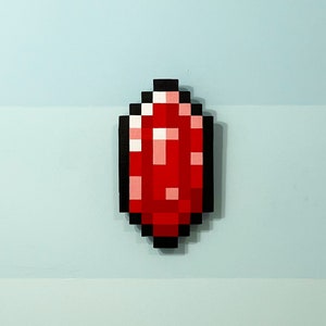 Könnte beinhalten: Ein roter, pixelig gestalteter Edelstein, der einem Minecraft-Diamanten ähnelt, mit schwarzem Umriss.