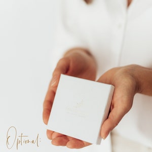 Puede incluir: Una caja de regalo blanca con un peque&ntilde;o dise&ntilde;o de hoja y el texto "Zarte Sch&auml;tze" en letras doradas. El texto "Optional: Die Geschenkschachtel ist optional im Warenkorb dazubuchbar und bei den Nylonarmb&auml;ndern NICHT Standardm&auml;&szlig;ig dabei." est&aacute; escrito debajo de la caja.