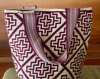 May include: A woven tote bag with a geometric pattern in burgundy and cream. The bag has sturdy handles and a spacious interior. The design features repeating cross-like shapes, creating a visually appealing and functional accessory.