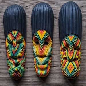 May include: Three black wooden masks with colorful beaded designs. The masks have geometric patterns in shades of yellow, orange, green, and red.