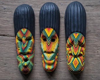 May include: Three black wooden masks with colorful beaded designs. The masks have geometric patterns in shades of yellow, orange, green, and red.