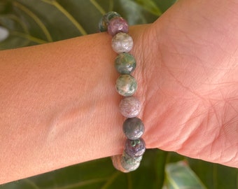May include: A bracelet made of green, pink, and brown agate beads. The beads are round and have a natural, polished finish.