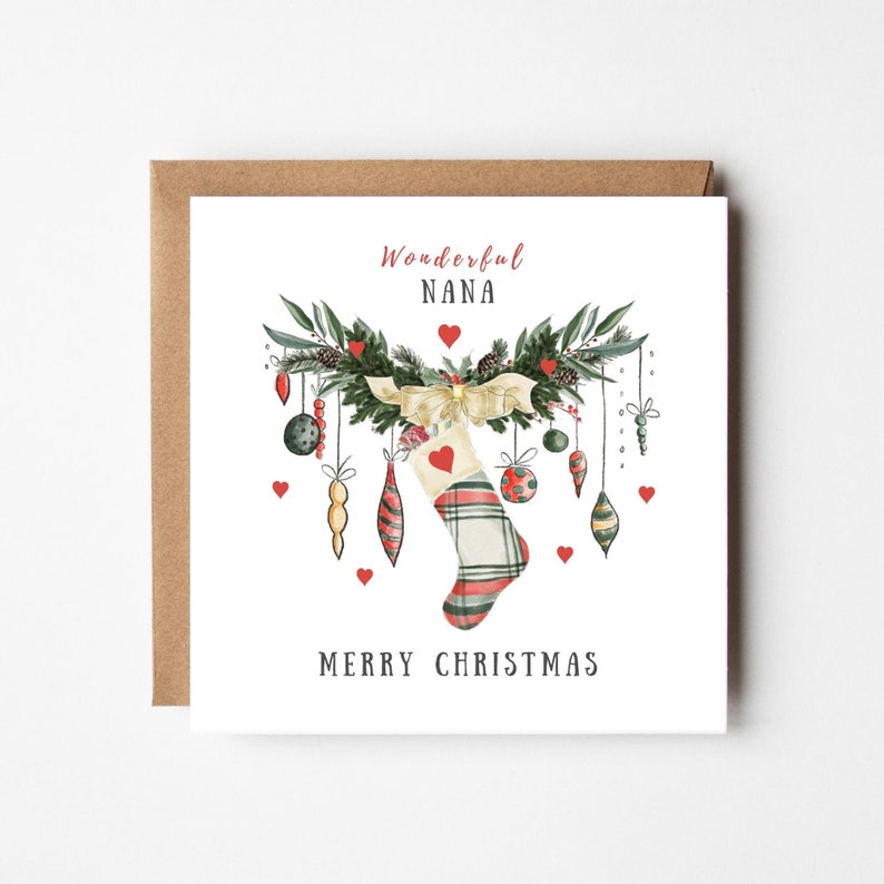 Op de afbeelding: Vierkante kerstkaart met een bruine rand. De kaart toont een aquarel illustratie van een kerstsok, ornamenten en groen. De tekst luidt "Wonderful NANA" en "MERRY CHRISTMAS" in een feestelijk lettertype.