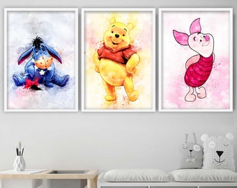 May include: Set of three framed watercolor prints featuring Winnie the Pooh characters. Includes Eeyore, Winnie the Pooh, and Piglet. Each print has a white border and is displayed against a white wall. The artwork has a soft, colorful, and whimsical style.