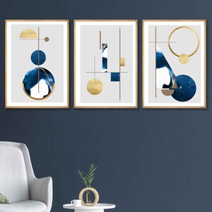 May include: Three framed abstract art prints with a gray background and geometric shapes in gold and blue. The shapes include circles, squares, and triangles.