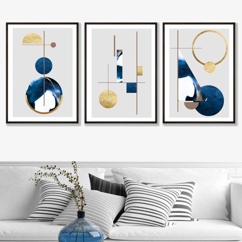 May include: Three framed abstract art prints with geometric shapes in shades of blue and gold on a gray background.