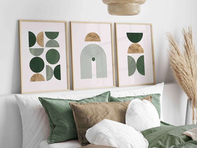 Puede incluir: Tres impresiones art&iacute;sticas abstractas enmarcadas con dise&ntilde;os geom&eacute;tricos en tonos verdes y dorados. Las impresiones se exhiben sobre una cama con cojines verdes y marrones y ropa de cama blanca. El arte presenta c&iacute;rculos, semic&iacute;rculos y l&iacute;neas arqueadas.
