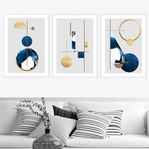 May include: Three framed abstract art prints with a gray background. Each print features a different geometric design with gold and blue accents.