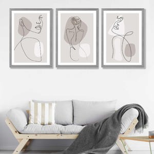 May include: Three framed prints featuring minimalist line drawings of figures against a light grey background. The figures are drawn in black lines and have abstract shapes in shades of grey.