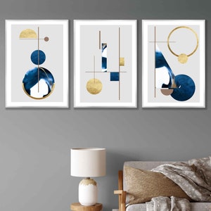 May include: Three framed abstract art prints with geometric shapes in shades of blue and gold on a white background.
