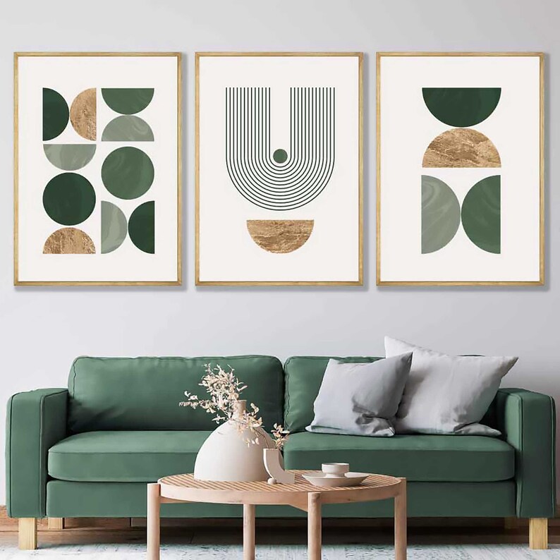 Puede incluir: Tres impresiones art&iacute;sticas abstractas enmarcadas. Cada impresi&oacute;n presenta formas geom&eacute;tricas en tonos verdes y dorados sobre un fondo crema. Los marcos son dorados. La obra de arte se exhibe sobre un sof&aacute; verde.