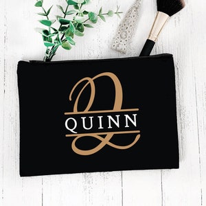 May include: Black canvas makeup bag with a gold monogram of the letter "Q" and the name "QUINN" in white lettering.