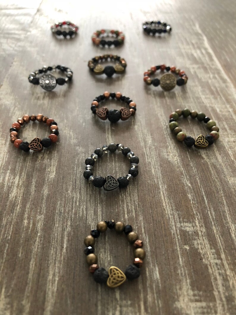 Puede incluir: Una colecci&oacute;n de diez pulseras de cuentas con cuentas de roca volc&aacute;nica y un dije de nudo celta. Las pulseras son de varios colores, incluyendo negro, marr&oacute;n, verde y plateado.