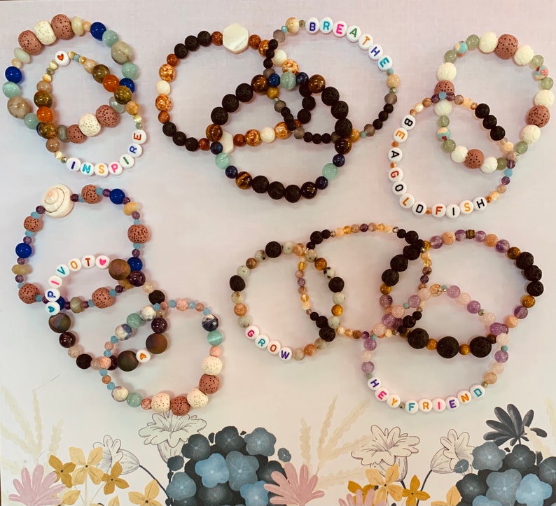 Pu&ograve; includere: Una collezione di braccialetti di perline in vari colori e trame. Alcuni braccialetti presentano perline con lettere che compongono parole come "inspire", "breathe", "be a goldfish", "pivot", "grow" e "hey friend". I braccialetti sono realizzati con una variet&agrave; di perline.