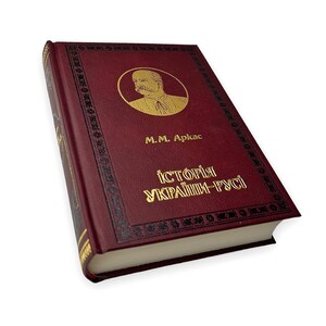 May include: A red hardcover book with gold lettering titled "Історія України-Руси" by M.M.  Apkas. The book features a portrait of a man on the cover.